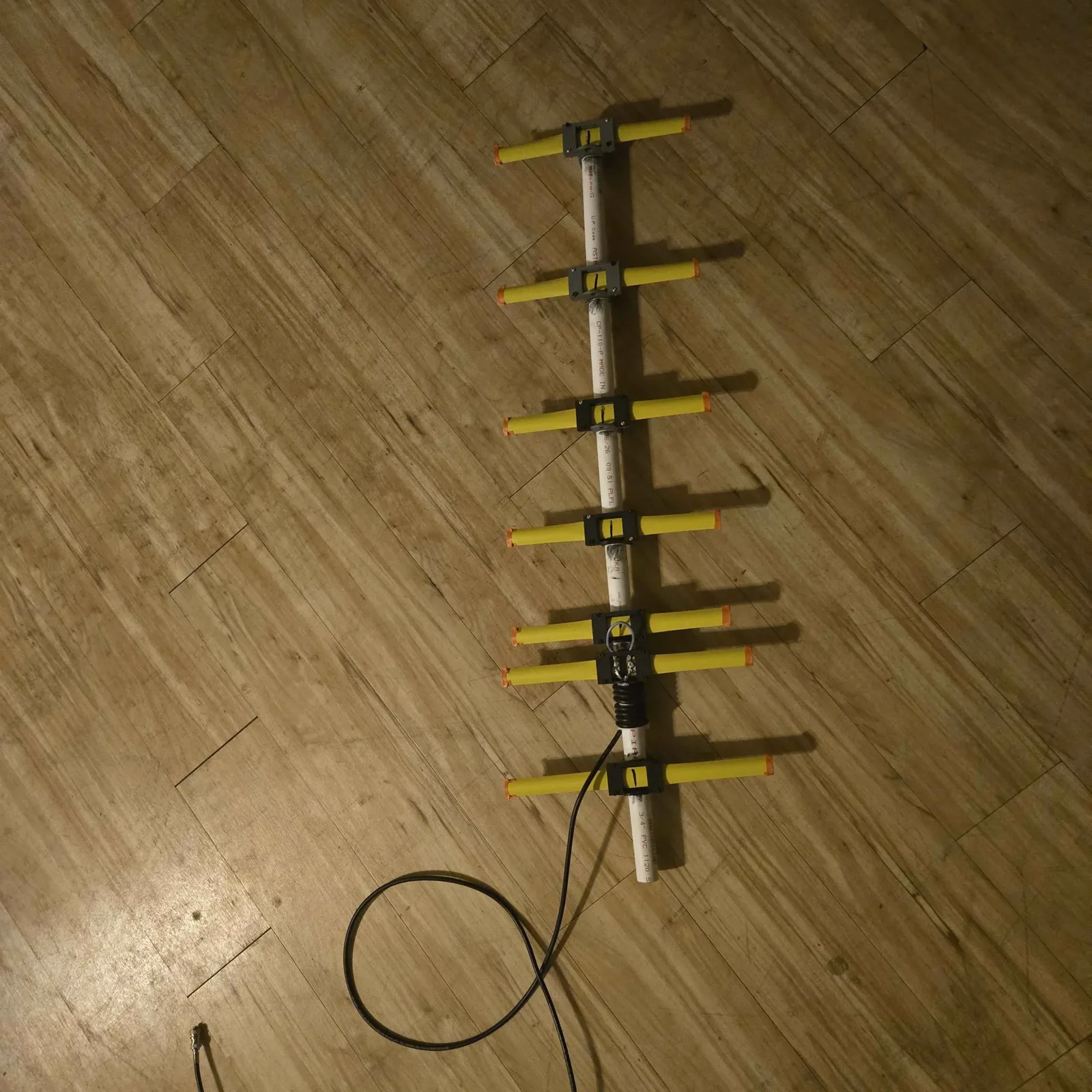 Completed 70 cm tape-measure Yagi antenna on a PVC boom with yellow tape elements, printed holders, and feedline attached